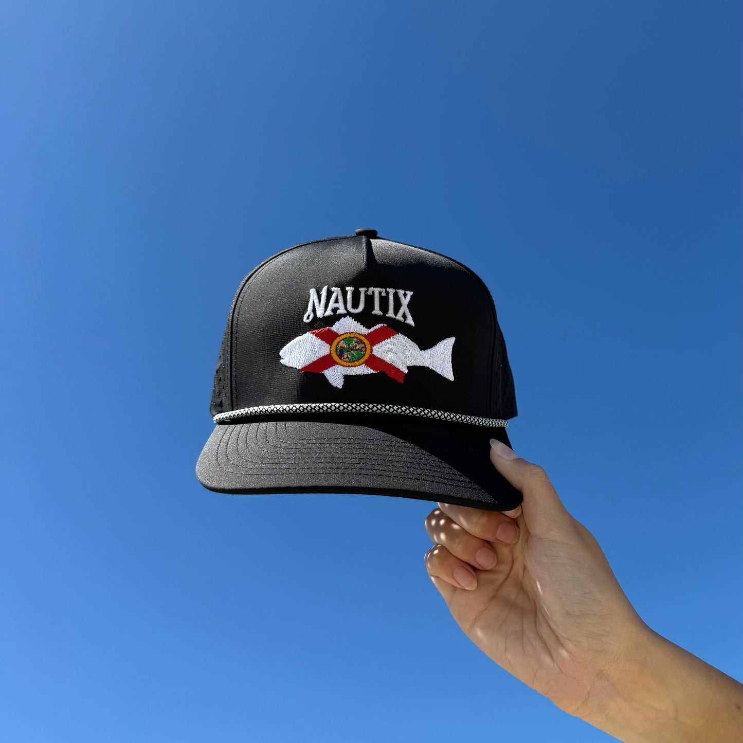 Person holding saltstate snapback hat in the sky 