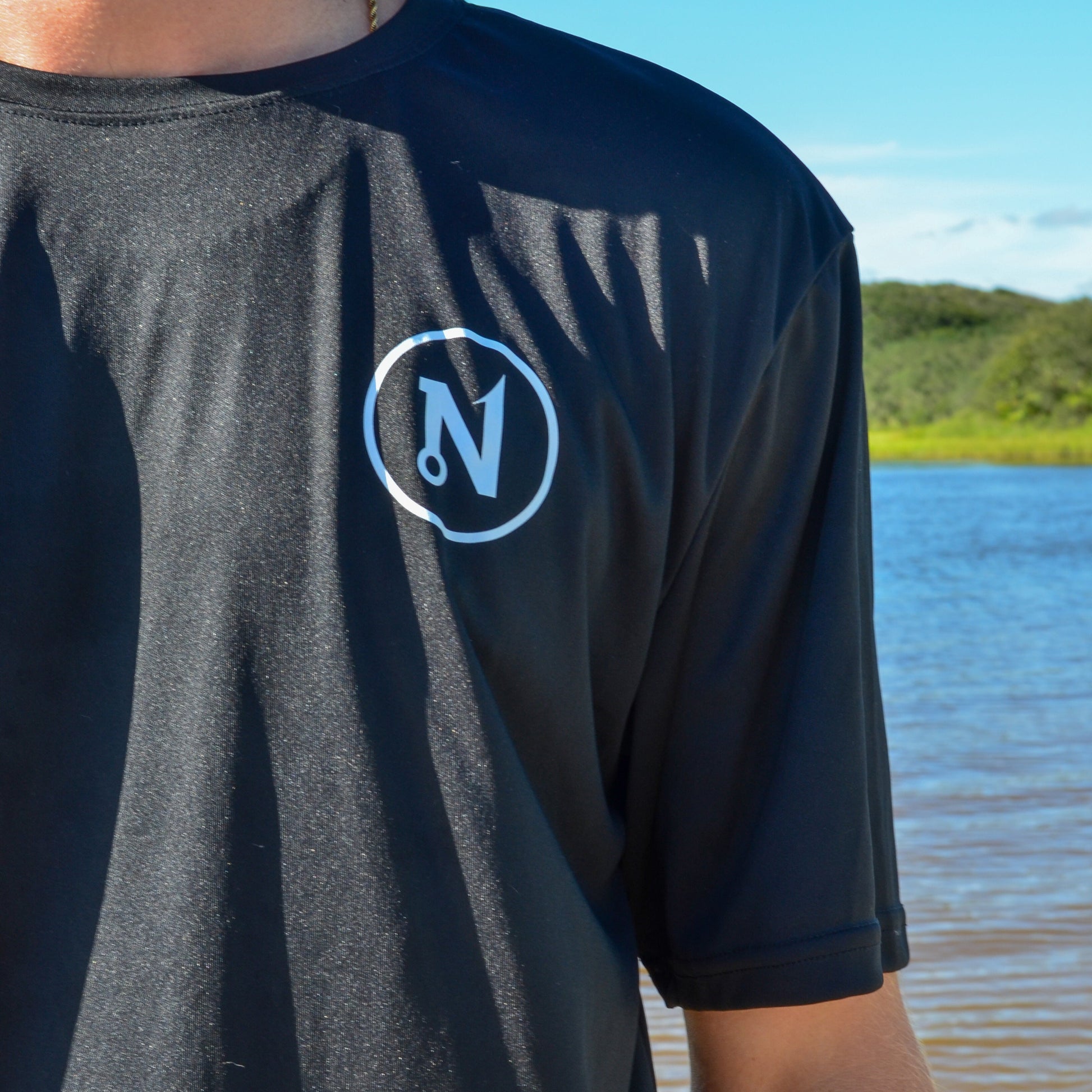 Close-up of Nautix circle icon printed on front of black Slam Art Cotton Tee