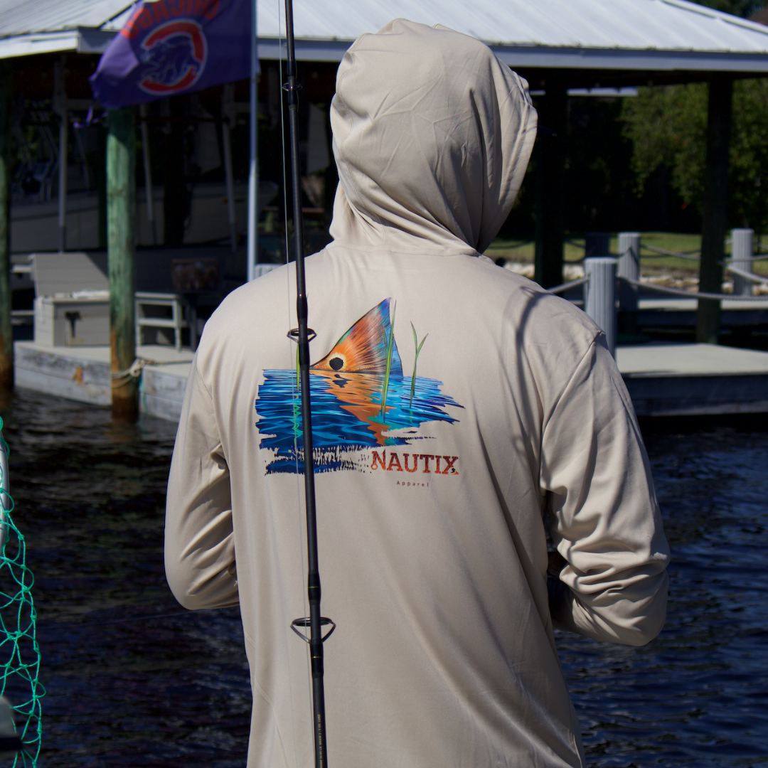 Person wearing sand Tailing Red performance hoodie near the water